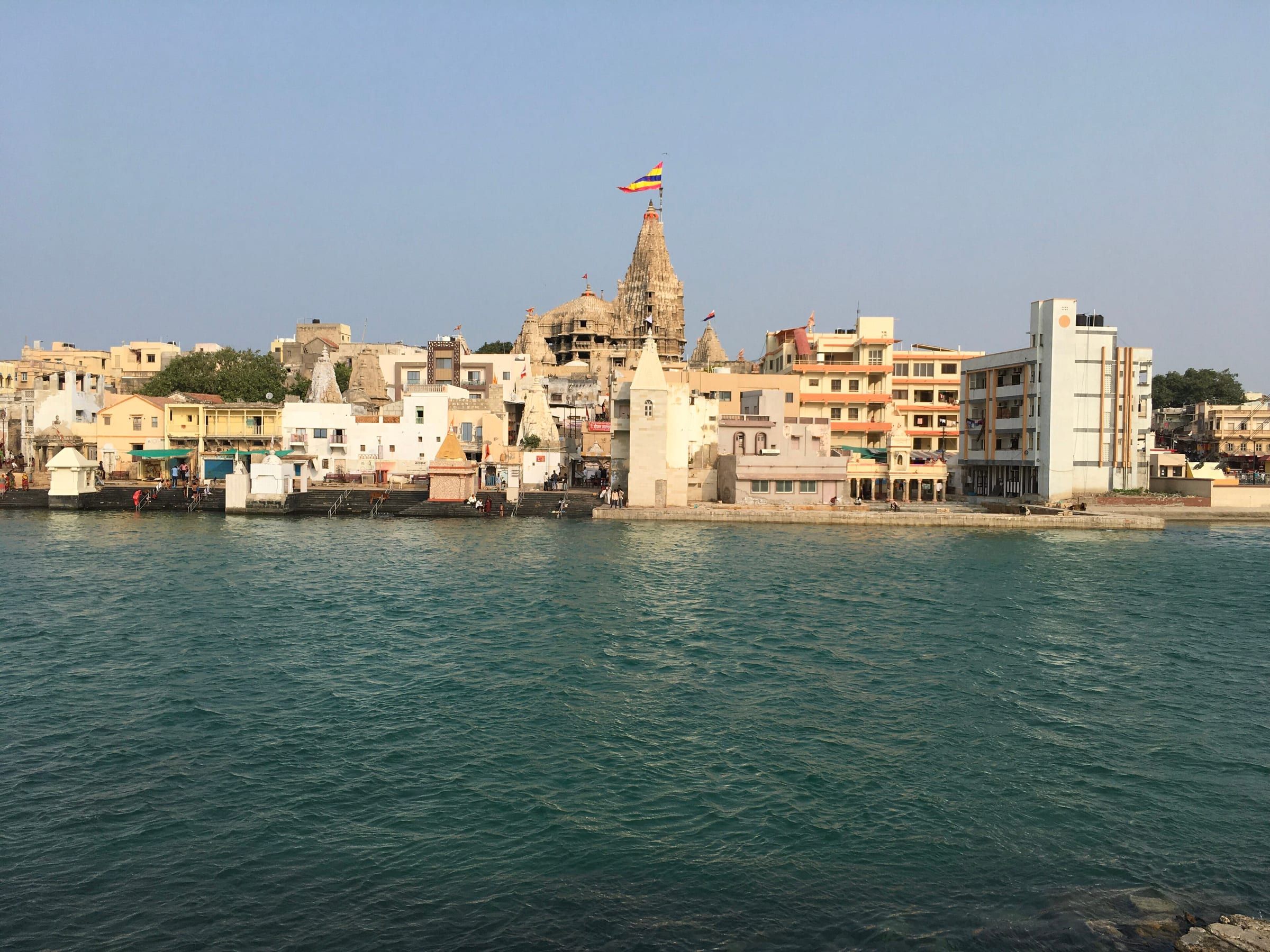 Dwarkadhish Temple's spire rising above Dwarka, seen across the Gomati river