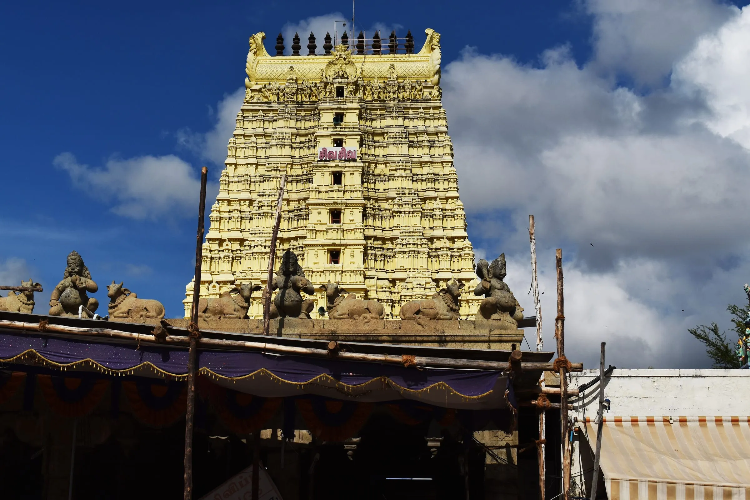 A gopuram, the carved gateway tower, of Ramanathaswamy Temple under a cloudy blue sky