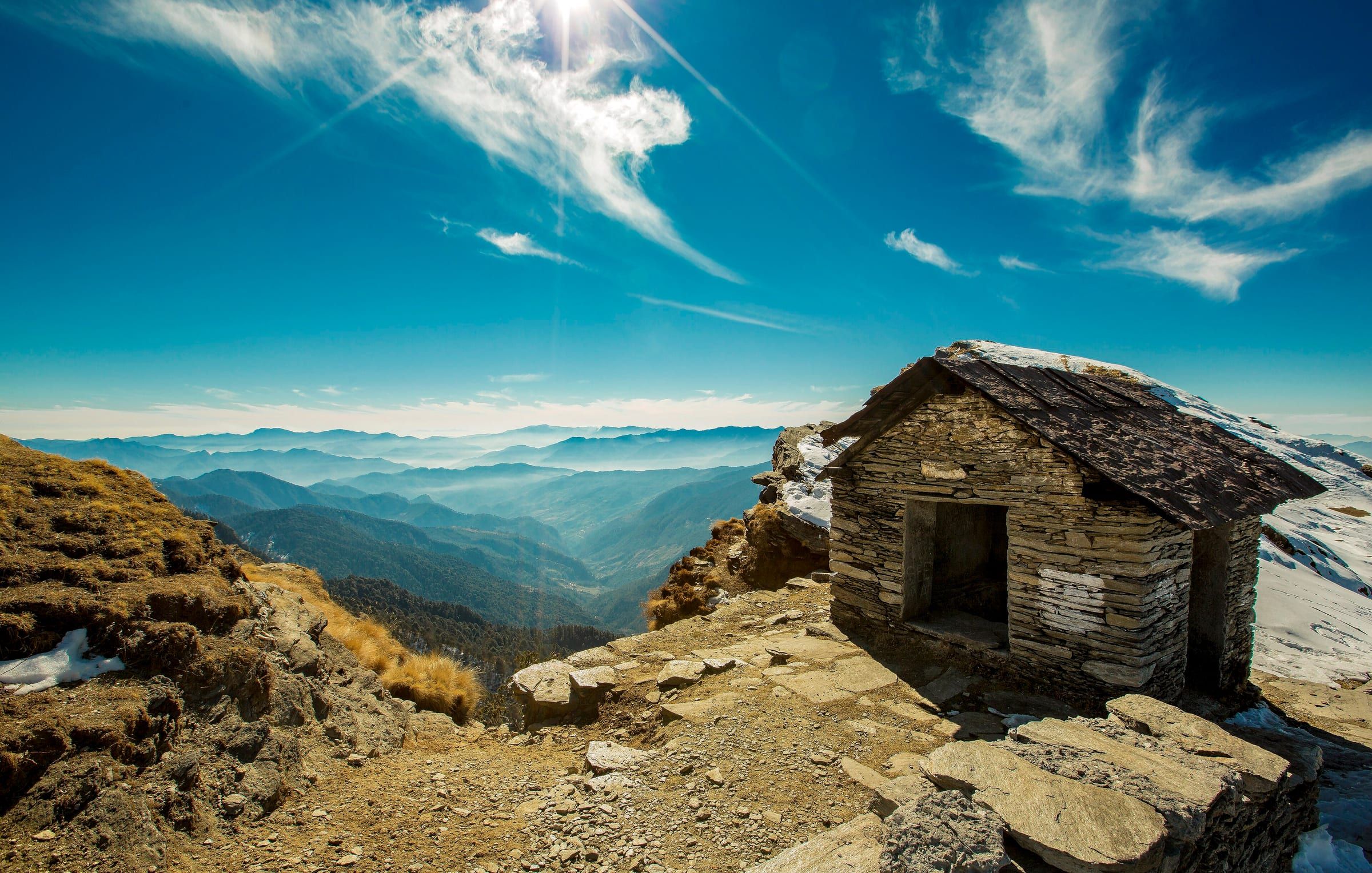 Tungnath Temple on its mountain ridge under a blue sky with clouds